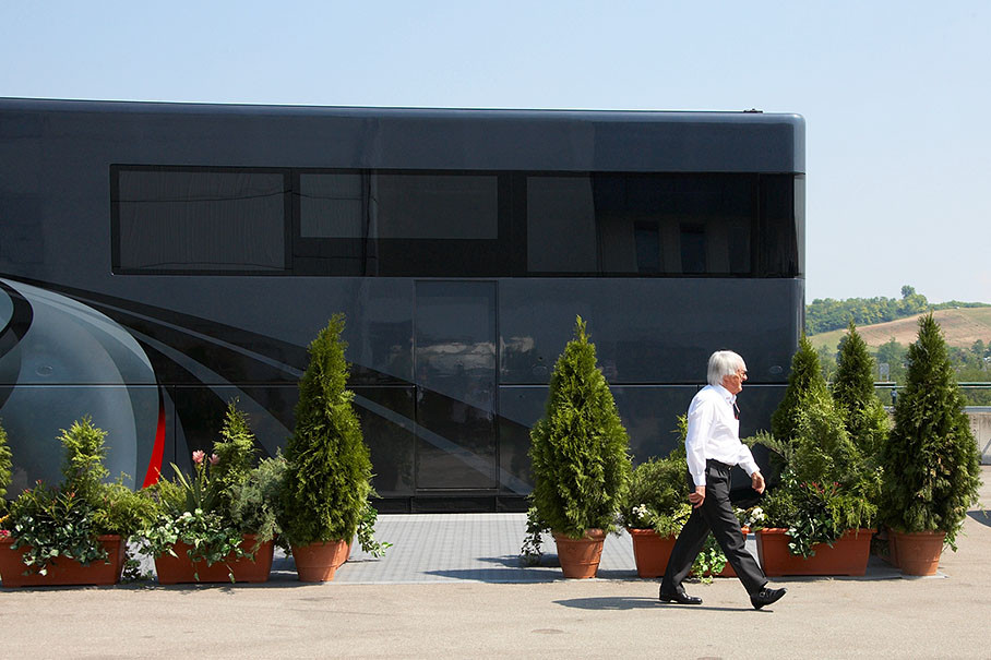 Bernie Ecclestone walks in front of his mobile office