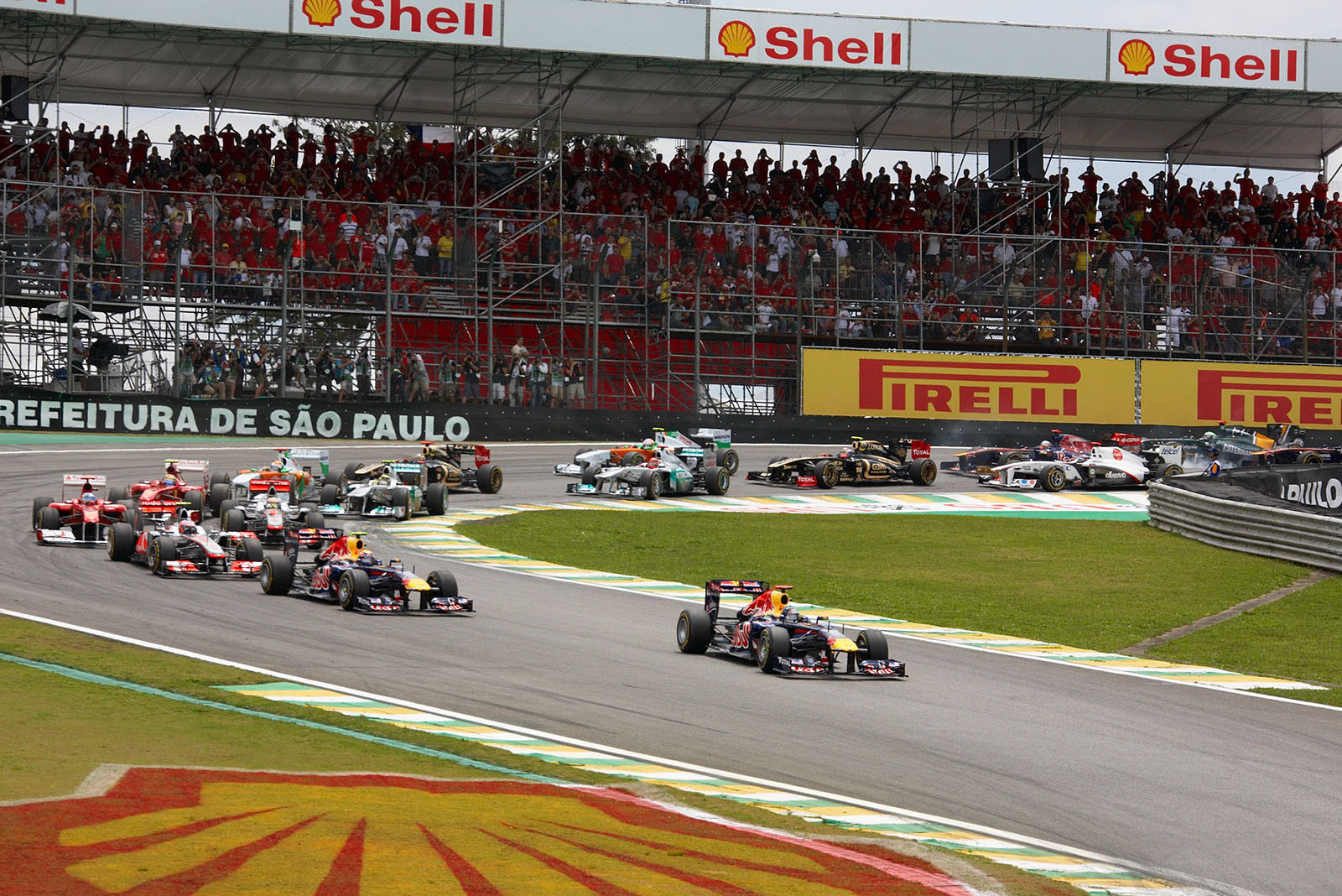 The start field squeezes through turn one, Red Bull's Sebastian Vettel leads in front of team mate Webber