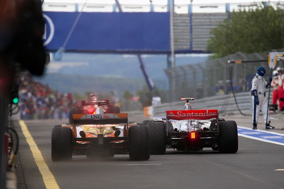 Rushing out to pit lane from his pit stop, Alonso squeezes his McLaren in front of Kovalainen's Renault