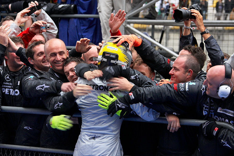 Third placed Nico Rosberg is being caressed by a bunch of happy Mercedes GP team members over parc ferme's fence