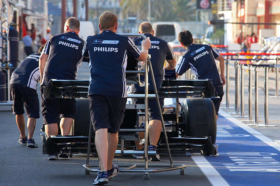 Williams mechanics roll the car back to their pits from scrutineering, always trying to hide the rear with the diffusers