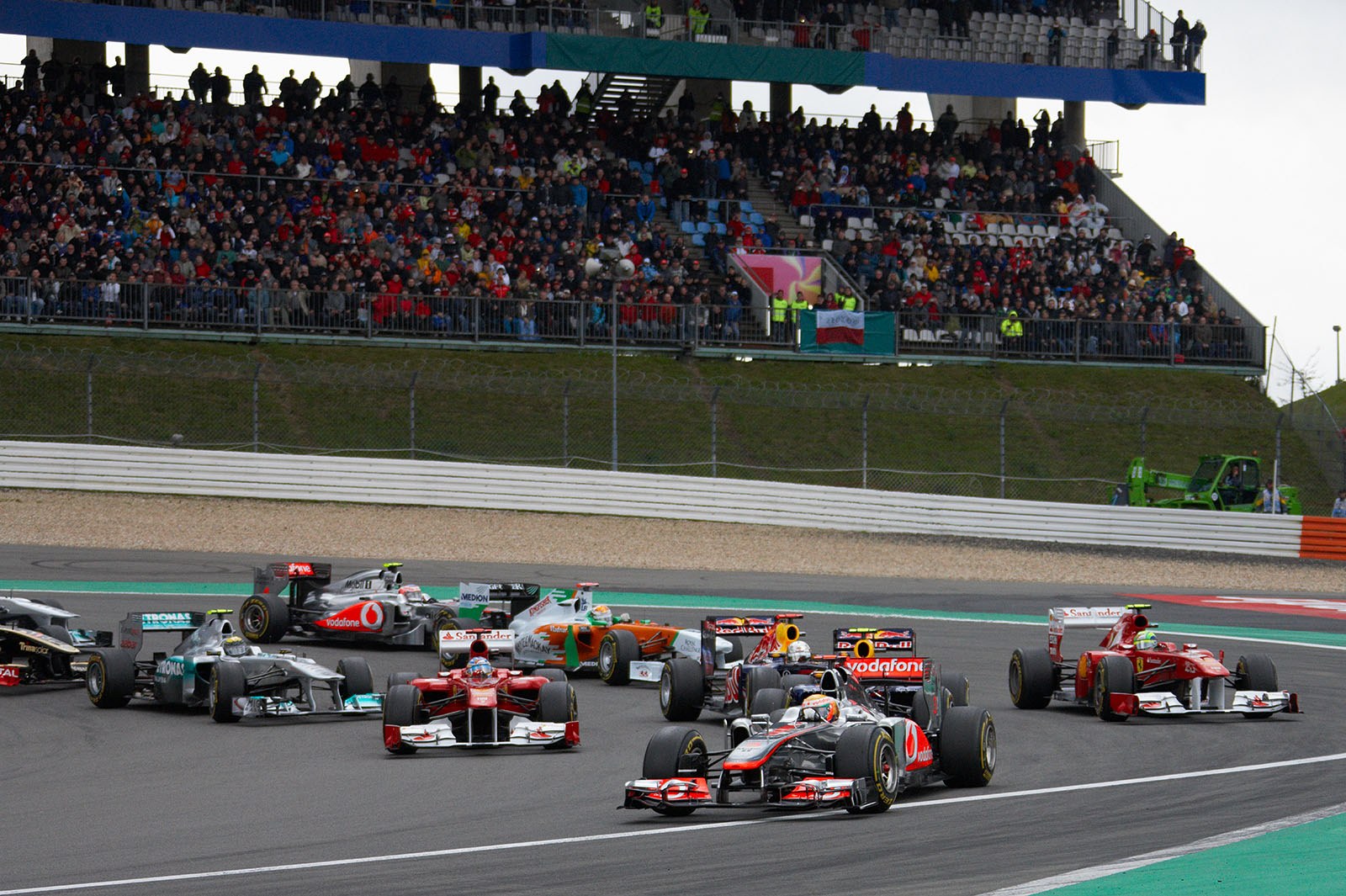The field goes around turn one, Hamilton leads Webber and Alonso