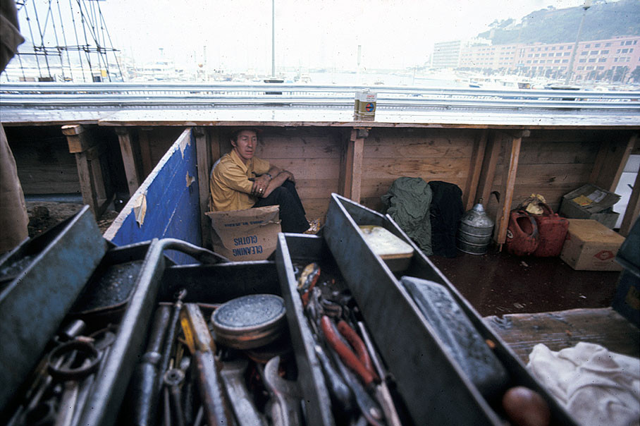 A mechanic hides from rain in the open pits besides Monaco's harbour