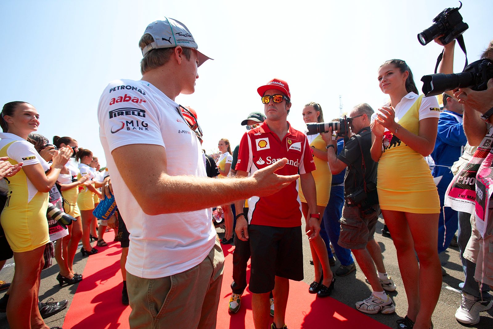 Ferrari's Fernando Alonso chats with Nico Rosberg on their way to drivers parade truck