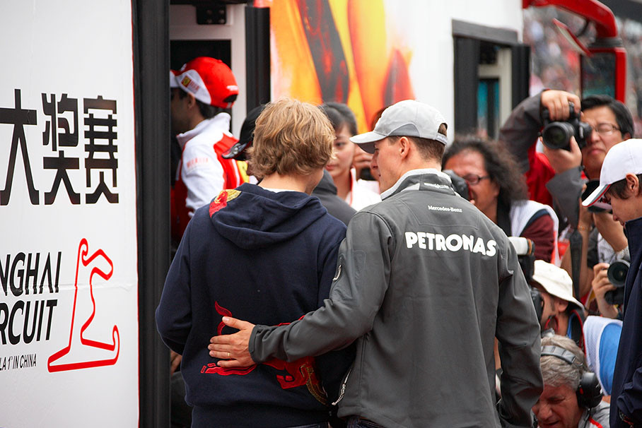 Schumacher uses a friendly gesture on Vettel as they enter the drivers parade truck