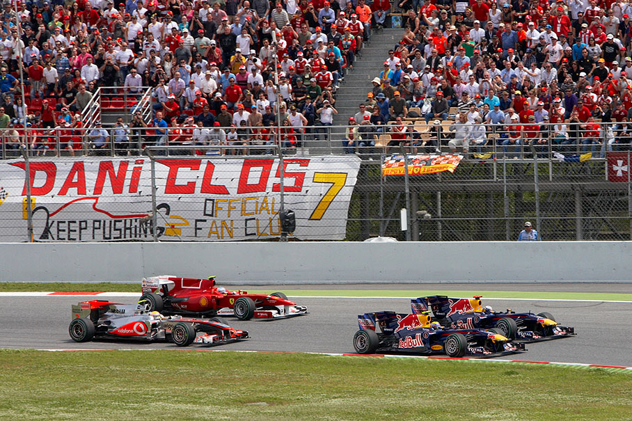 The start field approaches turn one, both Red Bulls in the lead