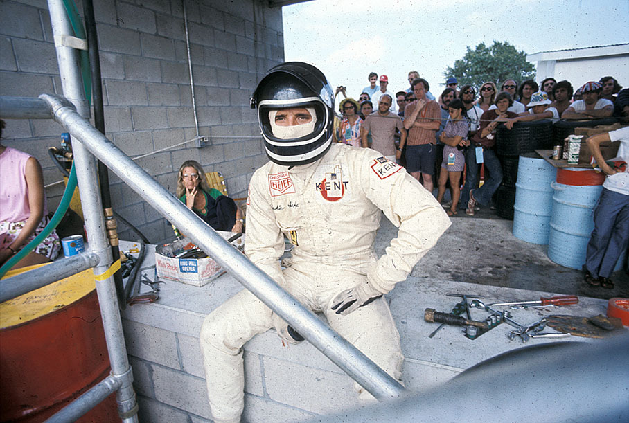 Jacky Ickx before his stint awaits the drivers exchange on his pit's wall under the eyes of watching fans