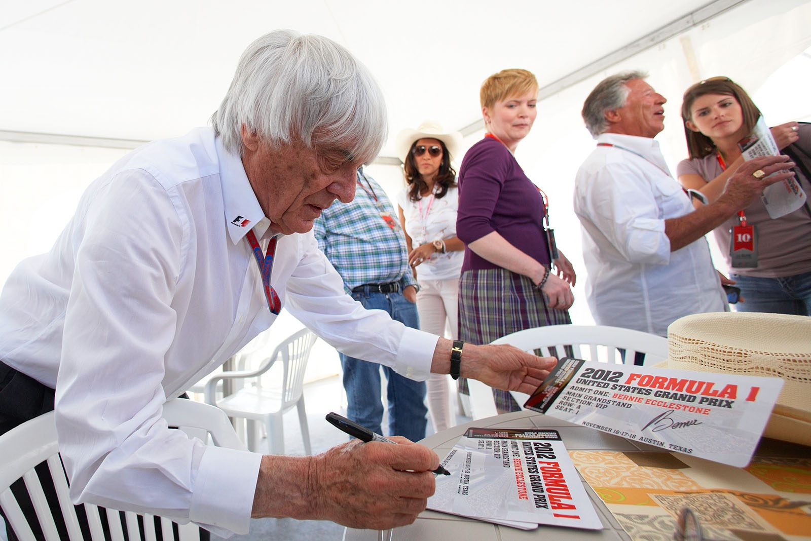 Bernie Ecclestone (Formula One Group CEO) signs some VIP charity tickets from Mario Andretti for the upcoming US GP in Austin