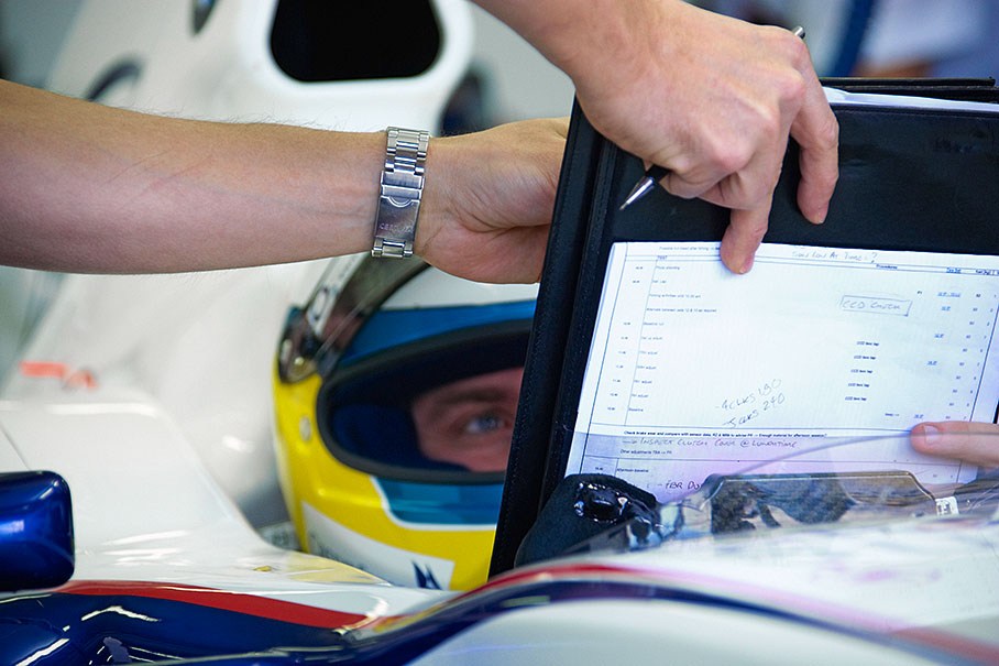 Nick Heidfeld in his car, looking at a data-sheet.