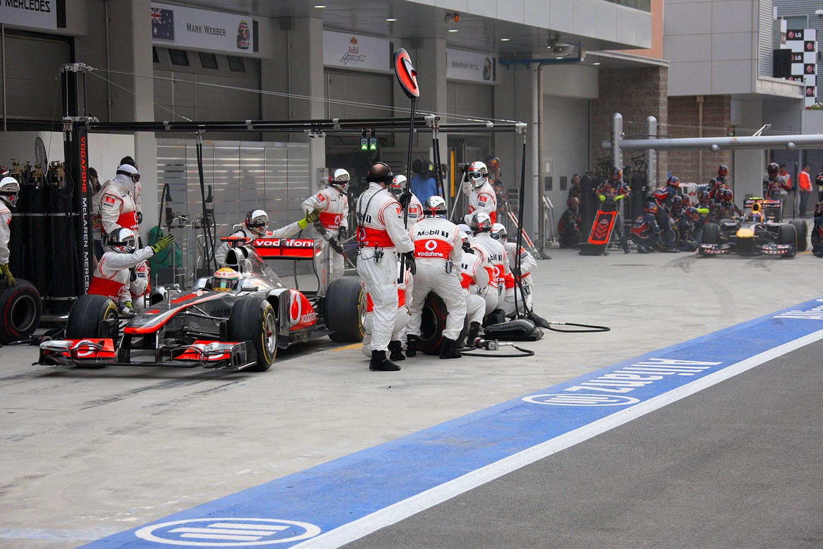 Lewis Hamilton ejects from McLaren pits in front of a pushing Webber