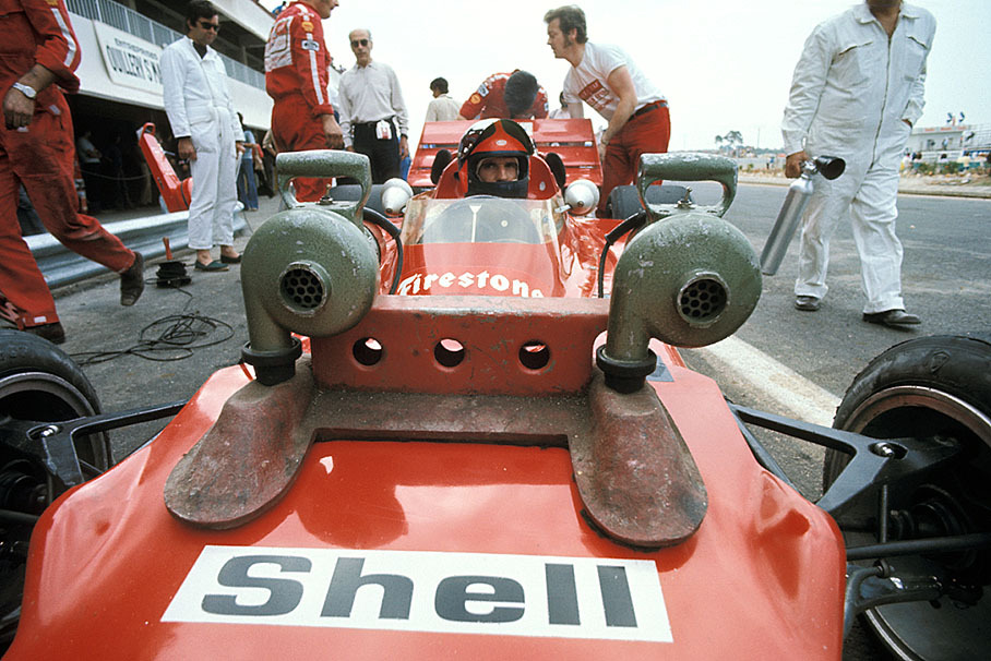 Emerson Fittipaldi sits waiting in his cockpit in front of the pits, having his Lotus-Cosworth 72D well-temperatured by two cooling devices