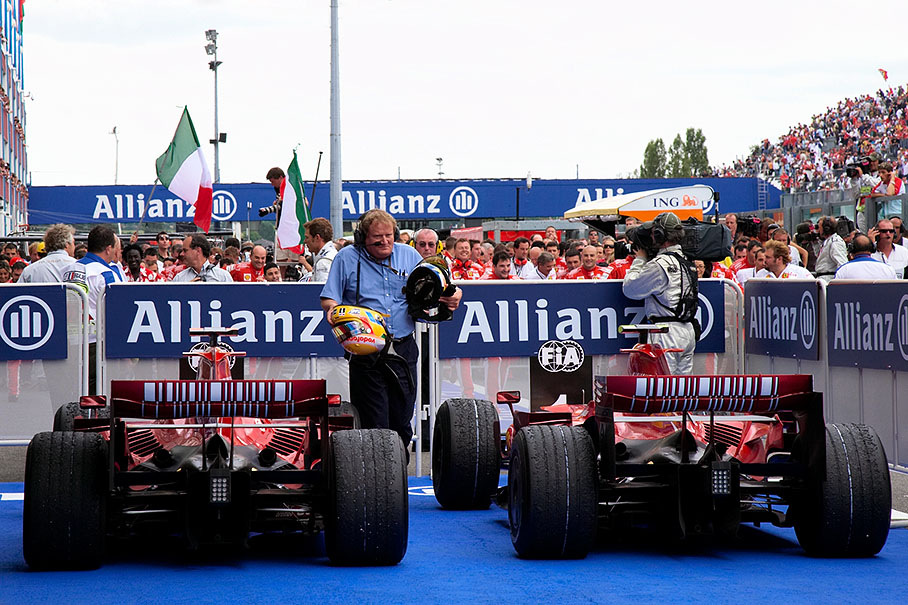 FIA technical delegate Jo Bauer collects helmet between the victorious Ferraris in parc ferme