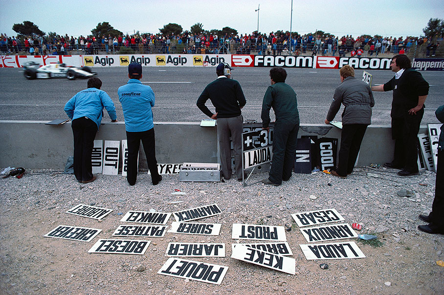 Frank Williams and his crew at the pitwall during the race as Jacques Laffite passes by