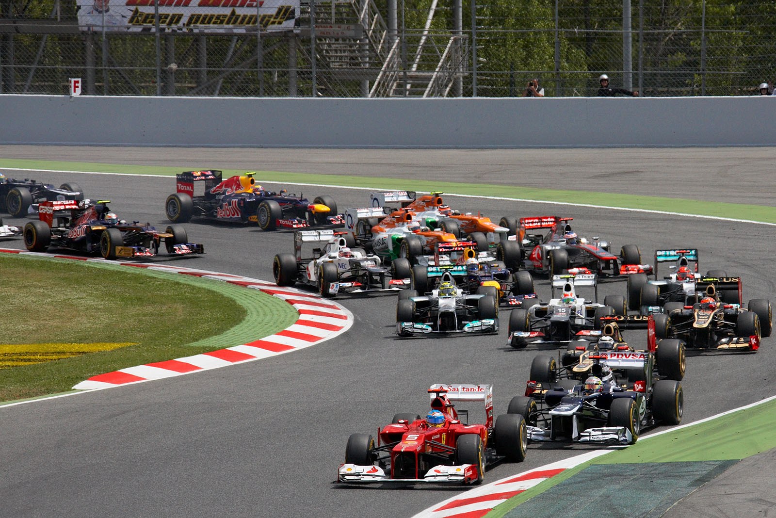 The start field of the Spanish Grand Prix 2012 squeezes through turns one and two - Ferrari's Alonso in the lead in front of Williams' polesetter Pastor Maldonado, chased by two Lotus-Renaults, Kobayashi in the Sauber-Ferrari and the two Mercedes works cars