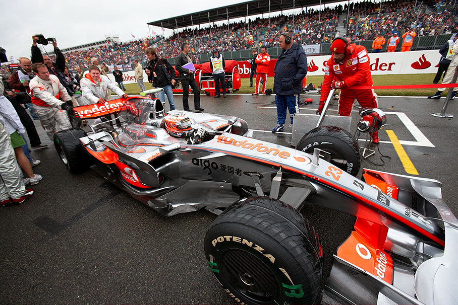 Heikki Kovalainen's car is being pushed to pole position with the helping hand of a Ferrari mechanic