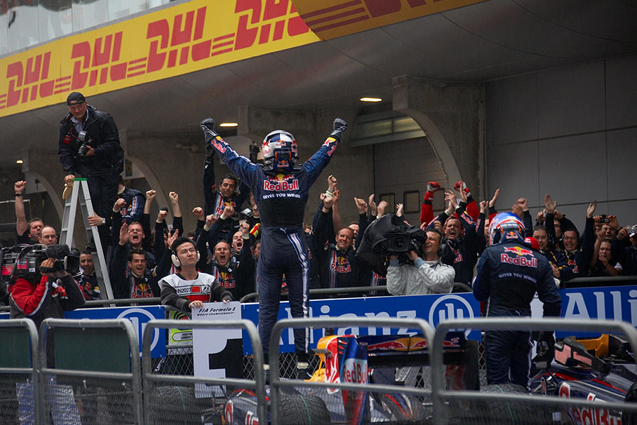 Race winner Sebastian Vettel and Red Bull Racing team mate Webber are welcomed at parc ferme after a long rainy race by a cheerful team crew