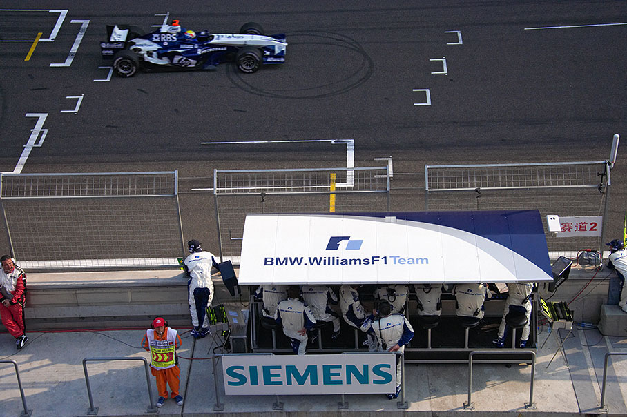 Mark Webber passing the Williams pitwall center