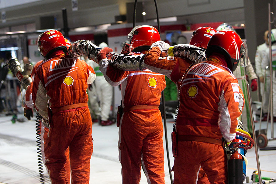 Ferrari mechanics carry a torn-away fuel rig down the pit lane after Felipe Massa left the pits earlier than the refueling had finished.