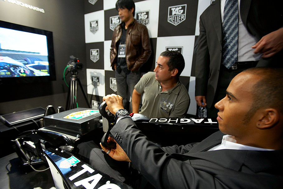 Lewis Hamilton, presenting his sponsor's new watch, does a simulated test drive