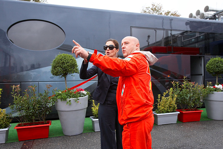 Slavica Ecclestone asks Ferrari's logistics manager Kotur for the way in front of Bernie's motorhome