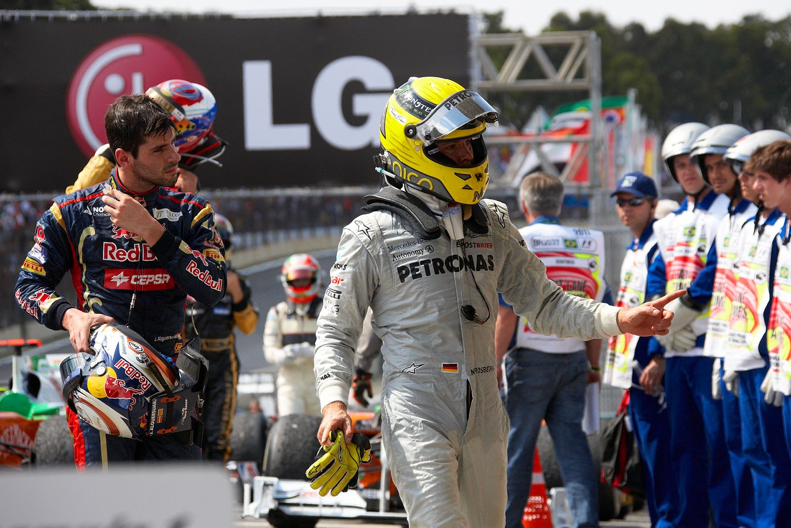 The other race drivers - Rosberg and Alguersuari - have finished the race and walk towards parc ferme after the Brazilian Grand Prix