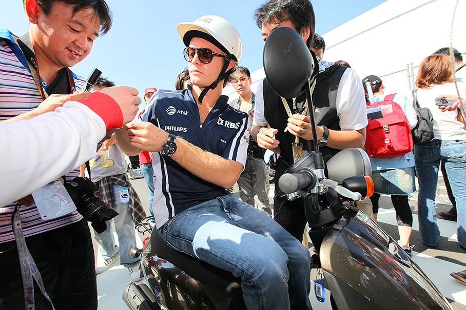 Nico Rosberg gives autographs to Japanese race fans from a scooter
