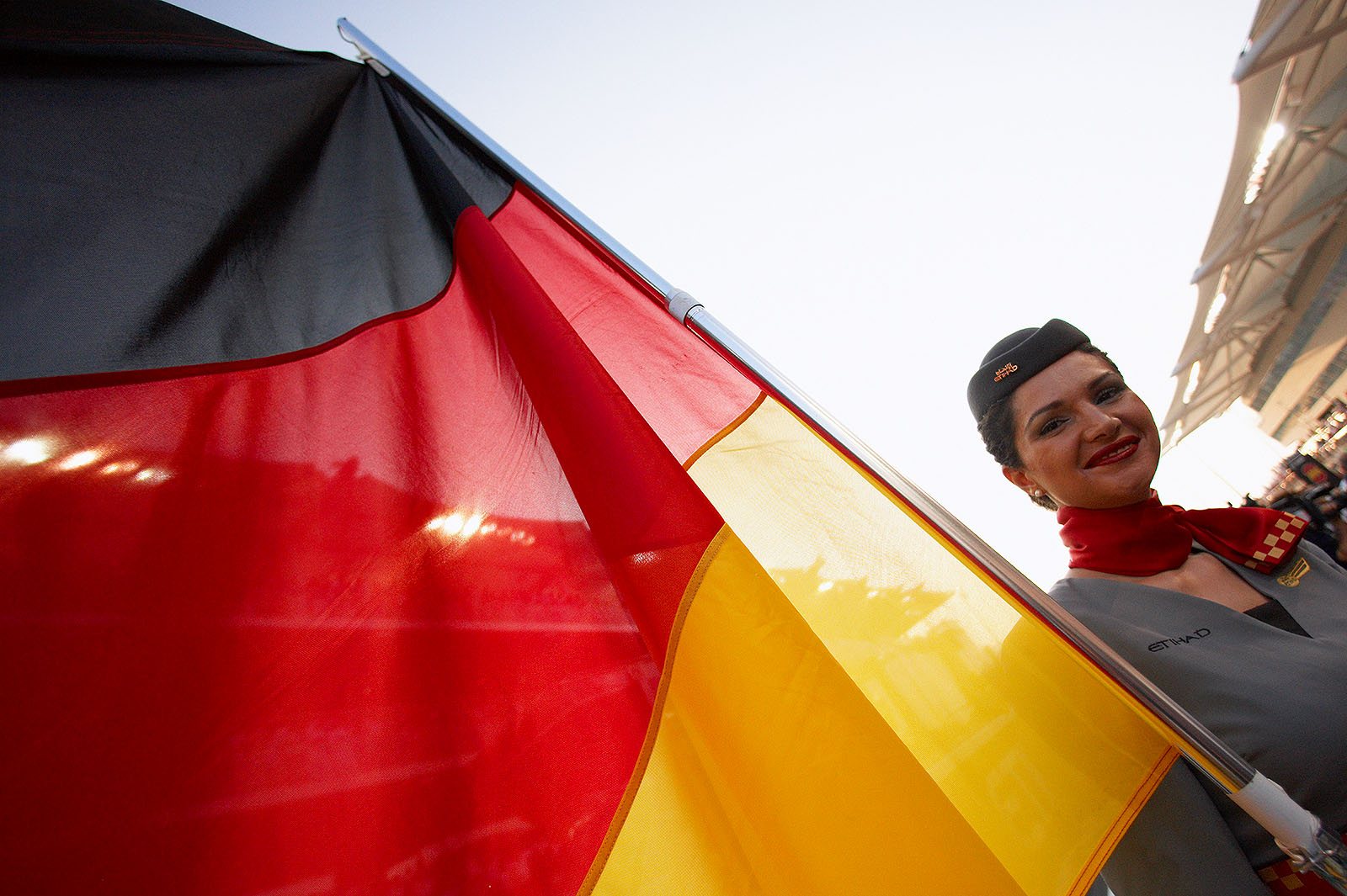 An Etihad Airways stewardess holds the German national banner on the grid