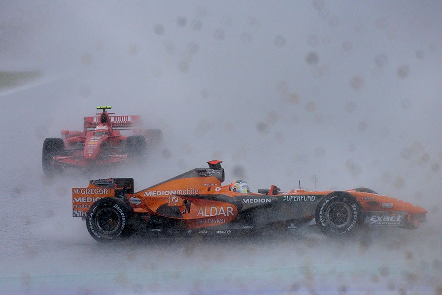 Sutil gyrates into gravel which is still flying in the foreground raised by Button's Honda