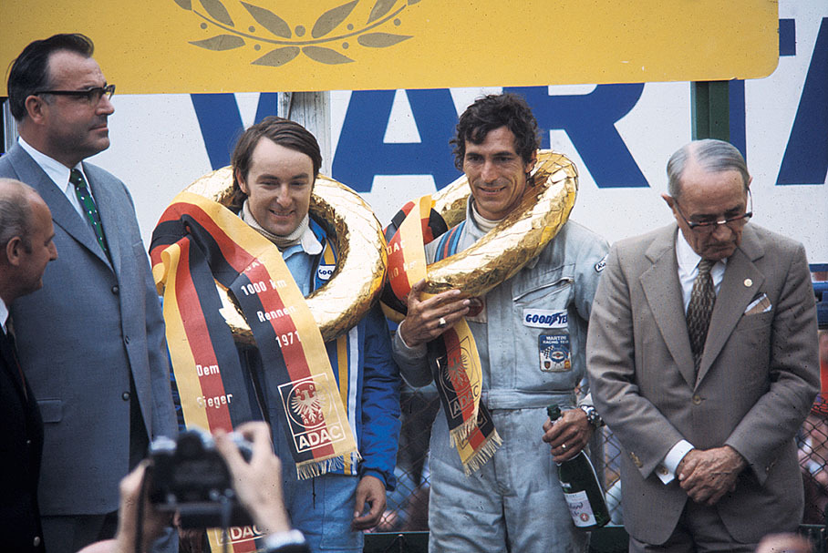 Prime minister of Rhineland-Palatinate and later German chancellor Helmut Kohl towers above podium ceremony for victorious Porsche 908/3 drivers Gerard Larrousse (F) and Vic Elford (GB)